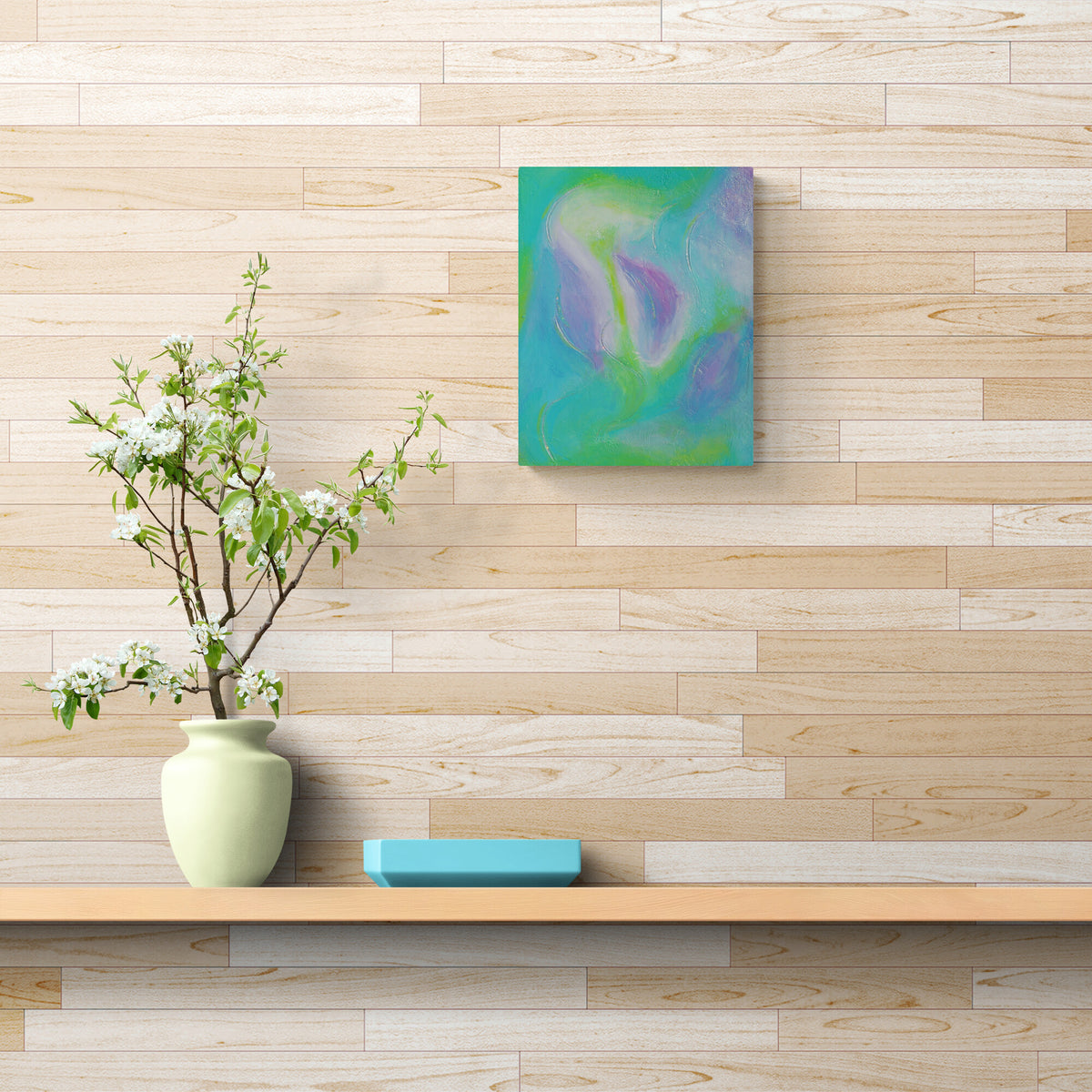 An abstract painting with swirling teal, green, and purple colors hangs on a light wood paneled wall above a wooden shelf with a pale green vase of white blossoms and a small blue block.
